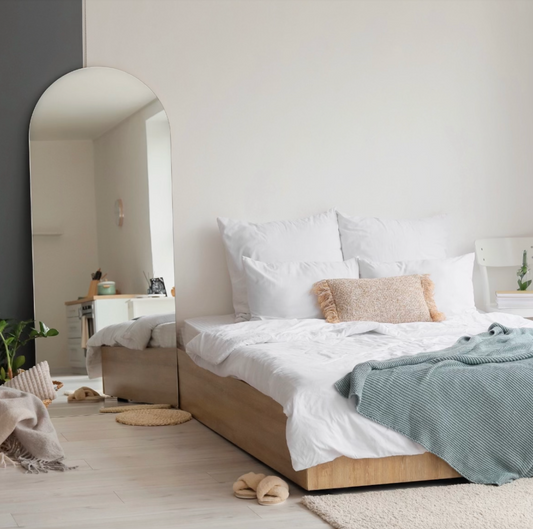 Studio with bed and arched floor length mirror.